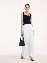 A lady wears wide pants and a crop top.
